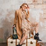 attractive-stylish-blonde-woman-beige-coat-sitting-suitcases-against-wall-street