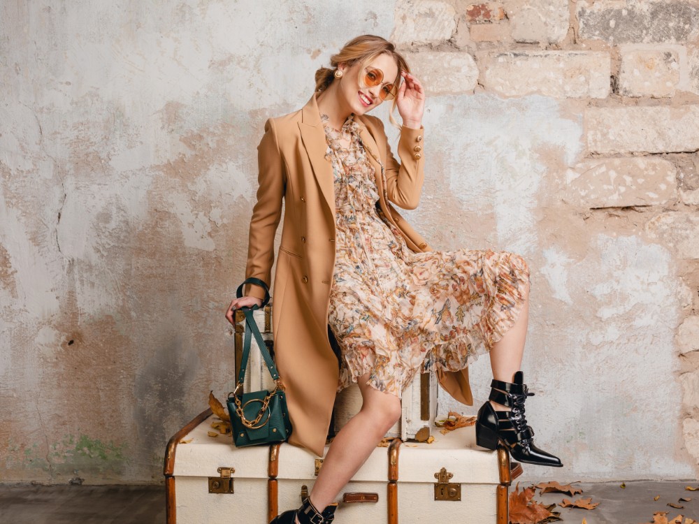 attractive-stylish-blonde-woman-beige-coat-sitting-suitcases-against-wall-street